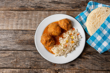 Mexican meatballs with red sauce and rice on wooden background