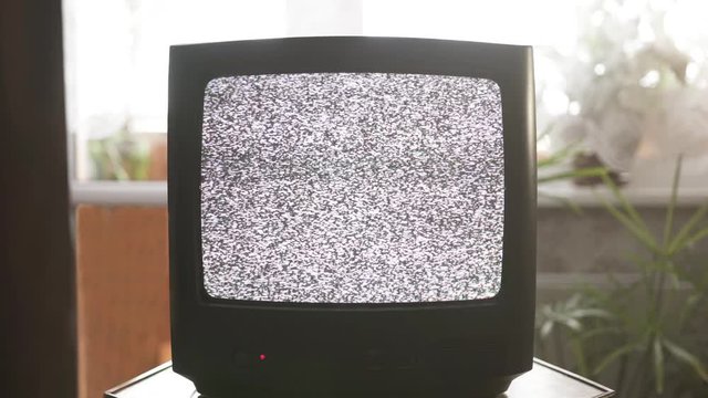 Old analog tv set in vintage interior. The screen shows noise. No signal.