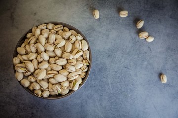 Pistachios nuts in brown plate on the dark background, captured from top