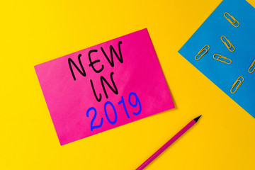 Writing note showing New In 2019. Business concept for what will be expecting or new creation for the year 2019 Blank paper sheets message pencil clips binder plain colored background