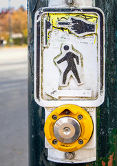 Push to walk button. Well used worn crosswalk button to activate traffic light. Blind and deaf-friendly sign.