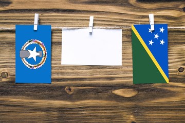 Hanging flags of Northern Mariana Islands and Solomon Islands attached to rope with clothes pins...