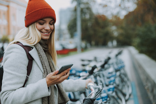 Young Girl Using Gadget For Rental Bike In City