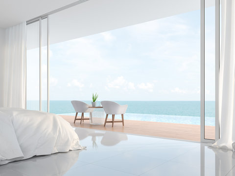 Modern luxury white bedroom 3d render.There is a minimalistic building with white beds and chairs. There is a large open sliding door overlooking the infinity pool and sea view.