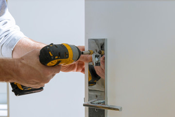 Carpenter fixing lock in door with home
