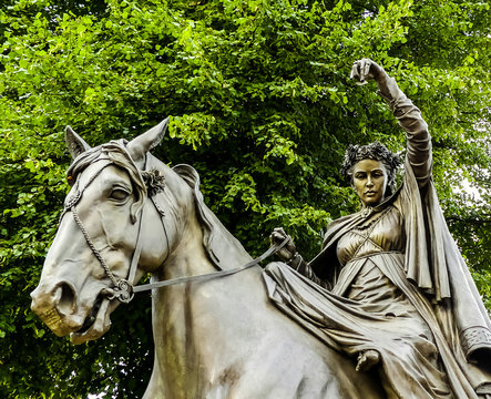 Partial view of the bronze statue of Banbury's Fyne Lady, astride a horse. From the nursery rhyme. Set in South Bar, Banbury. Background of tree, looking upwards. Oxfordshire. England.
