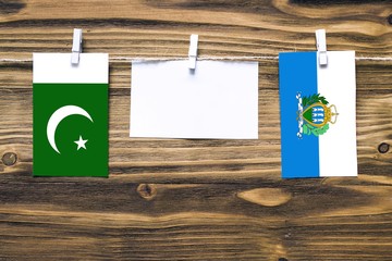 Hanging flags of Pakistan and San Marino attached to rope with clothes pins with copy space on...