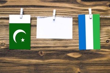 Hanging flags of Pakistan and Sierra Leone attached to rope with clothes pins with copy space on...