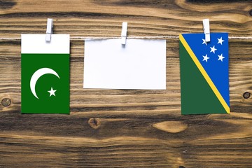 Hanging flags of Pakistan and Solomon Islands attached to rope with clothes pins with copy space on...