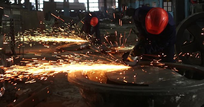 Male hand cuts off pieces of water pipe with angle grinder. Cutting of a steel with splashes of sparks at construction site. Sparks during cutting of metal angle grinder