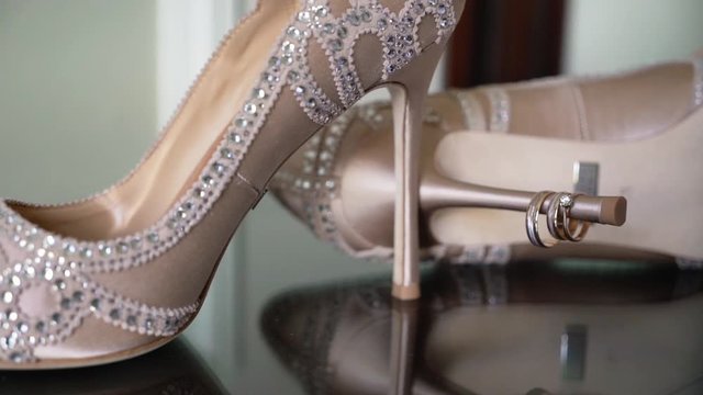 Wedding rings and bridal shoes. Pair of marriage symbols. Love of bride and groom becoming wife and husband. Matrimony symbol