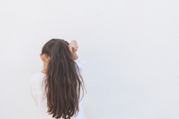 Fototapeta premium Little disappointed girl feeling upset and offended. Rear view of a young lady lost or being offended by her parents. Cute school girl turning her head to the side