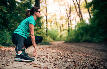 Active young woman stretching legs before jogging in the nature