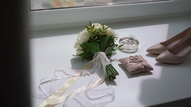 Wedding rings, flowers bouquet and bridal shoes. Pair of marriage symbols. Love of bride and groom becoming wife and husband. Matrimony symbol