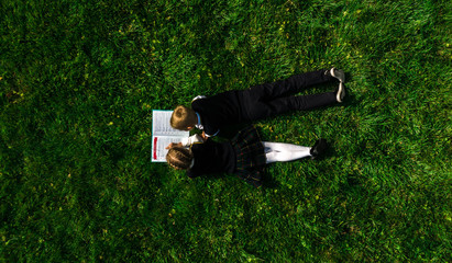 Children reading the book on the grass in summer. Top view