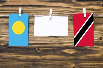 Hanging flags of Palau and Trinidad And Tobago attached to rope with clothes pins with copy space...