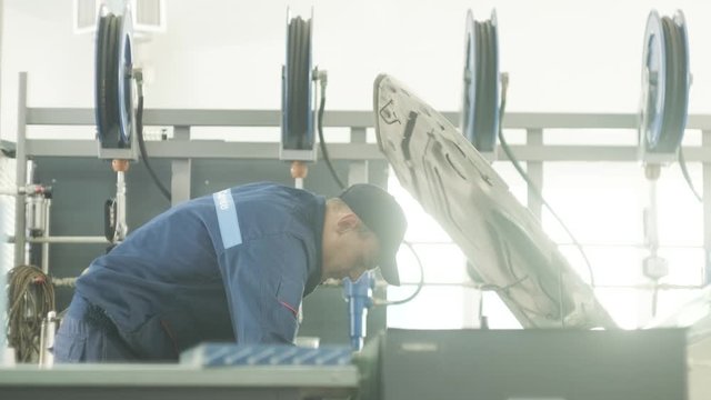 car service, repair, maintenance and people concept - auto mechanic man with lamp working at workshop