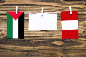 Hanging flags of Palestine and Peru attached to rope with clothes pins with copy space on white...