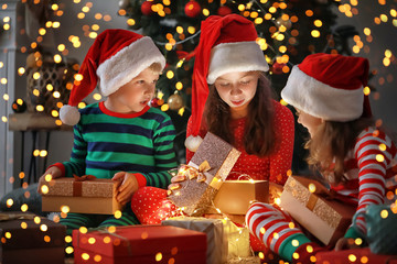 Cute little children opening magic Christmas gift at home