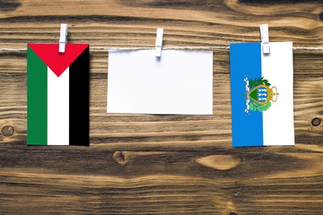 Hanging flags of Palestine and San Marino attached to rope with clothes pins with copy space on...