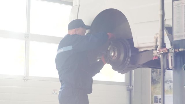 car mechanic replacing car wheel brake shoes of lifted automobile at repair service station