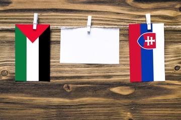 Hanging flags of Palestine and Slovakia attached to rope with clothes pins with copy space on white...