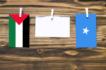 Hanging flags of Palestine and Somalia attached to rope with clothes pins with copy space on white...