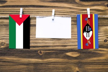 Hanging flags of Palestine and Swaziland attached to rope with clothes pins with copy space on...