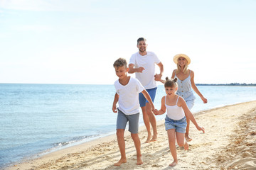 Happy family running on sea beach