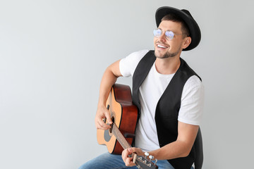 Handsome man playing guitar on light background