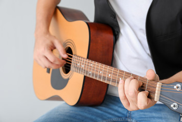 Fototapeta na wymiar Man playing guitar on light background, closeup