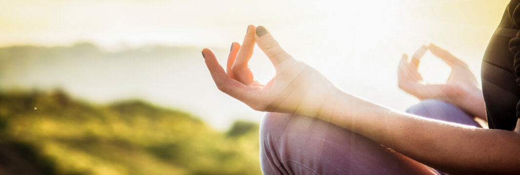 woman doing yoga in beautiful nature background at sunset or sunrise, focus on hand - mindfulness and mental health and hygiene background