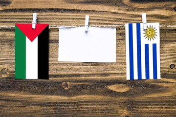 Hanging flags of Palestine and Uruguay attached to rope with clothes pins with copy space on white...