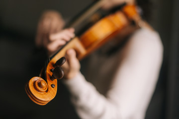 Beautiful woman musician plays the violin in her home, close-up. Female 's face is not visible. © dikushin