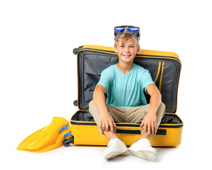 Cute little boy sitting in suitcase on white background