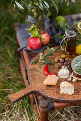 Delicious and romantic italian snack outside of a couple: wine, olives, bottle of olive oil, bread, fruits. Luxury lifestyle, healthy and gourmet food. Served on old rustic wooden board