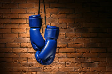 Pair of boxing gloves hanging against brick wall