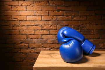 Pair of boxing gloves on table against brick wall