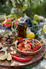 Romantic italian lunch outside for a couple: copper pan with delicious and spicy fried shrimps with...
