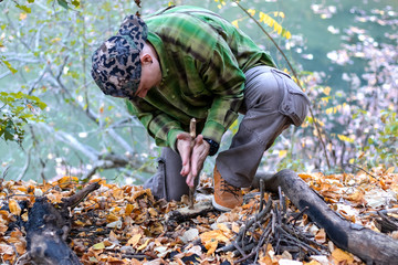 Man starting a fire in the wild using technique of friction with two sticks. Practicing survival...