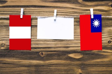 Hanging flags of Peru and Taiwan attached to rope with clothes pins with copy space on white note paper on wooden background.Diplomatic relations between countries.