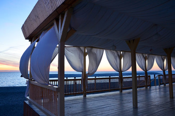 gazebo with curtains by the sea at sunset