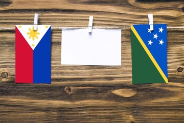 Hanging flags of Philippines and Solomon Islands attached to rope with clothes pins with copy space...