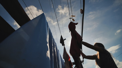 A young woman hangs clothes for drying on a summer day.