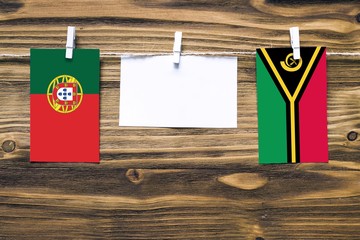 Hanging flags of Portugal and Vanuatu attached to rope with clothes pins with copy space on white...