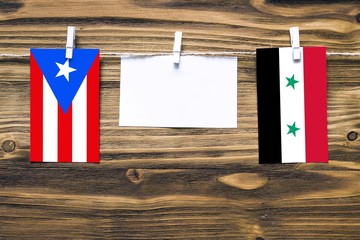 Hanging flags of Puerto Rico and Syria attached to rope with clothes pins with copy space on white...