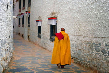 Tibetan monk, dressed in yellow, walking on the streets of the Tashilhunpo Monastery, in Shigatse.