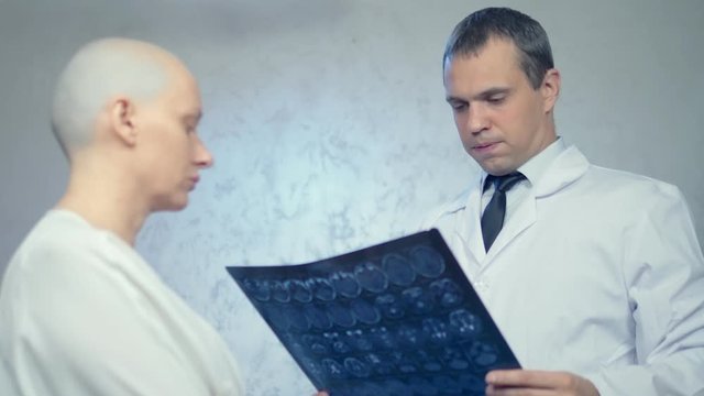 young bald woman at the doctor, consultation on the results of tomography, bad news.