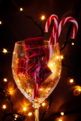 GLASS CUP WITH GIFT PACKS AND LAMPS OF CARAMEL LIGHTED BY LIGHTS. MERRY CHRISTMAS