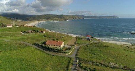 Aerial: Coastal village with houses and sea against sky on sunny day - Galicia, Spain